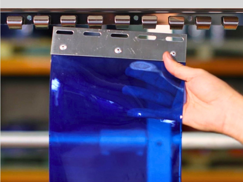 Hand holding a blue pvc strip curtain attached to a metal hanging plate.