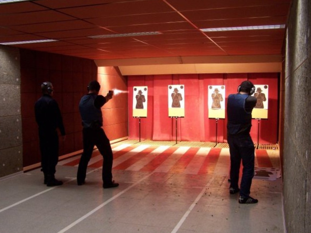 Group of officers training at an indoor shooting range with paper targets.