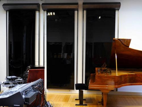 A music studio with black sound insulation curtains in the background.